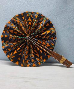 Ancestral Forest African Fan made from authentic 100% African wax cotton fabric, featuring a pattern inspired by African nature, a wooden handle, and leather details.<br/> <br/> <br/>