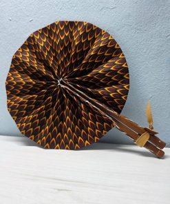 Ancestral Flame African Fan made from authentic 100% African wax cotton fabric, featuring a pattern inspired by flames and African symbols, a wooden handle, and leather details.